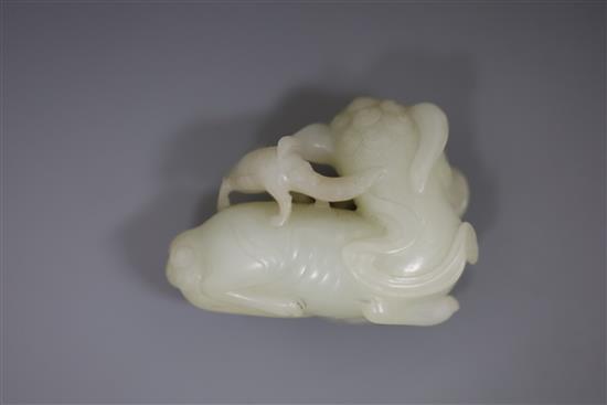 A Chinese pale celadon jade figure of a lion dog and cub, 18th/19th century, L. 6cm, wood stand